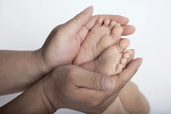 Moeders handen houden de voeten van haar zoon — Stockfoto