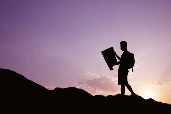 Silhouette of young man looking at a map — Stock Photo, Image