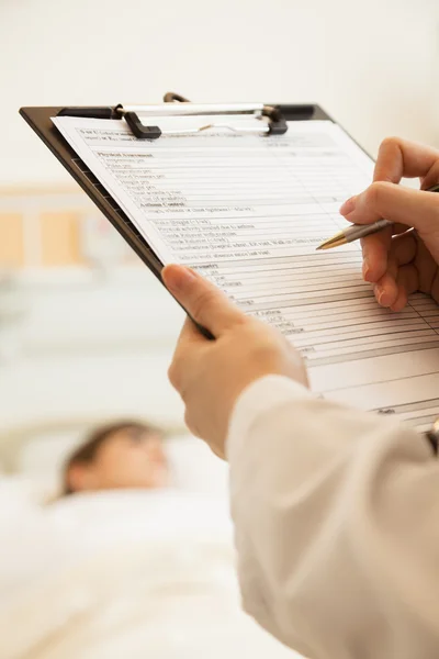 Doctor writing on a medical chart — Stock Photo, Image