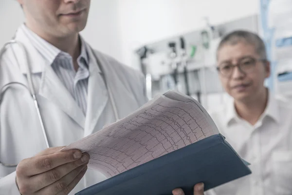 Doctor checking medical chart with patient — Stock Photo, Image