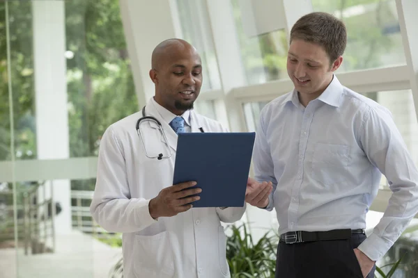 Médecin et patient discutant dossier médical — Photo