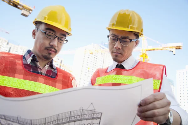 Architects looking at a blueprint outdoors — Stock Photo, Image