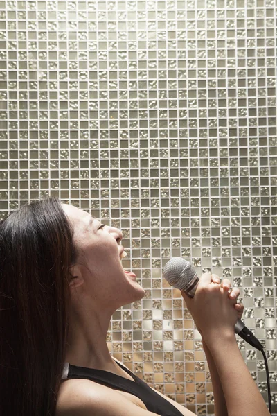 Woman singing into a microphone at karaoke — Stock Photo, Image