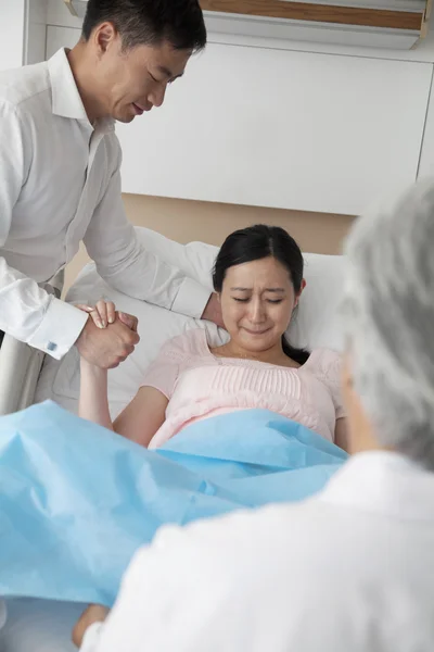 Women in labor holding her husbands hand with doctor — Stock Photo, Image