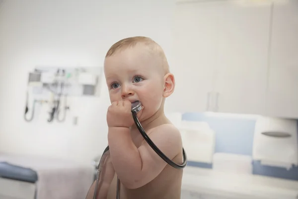 Curious baby holding and biting a stethoscope — Stock Photo, Image