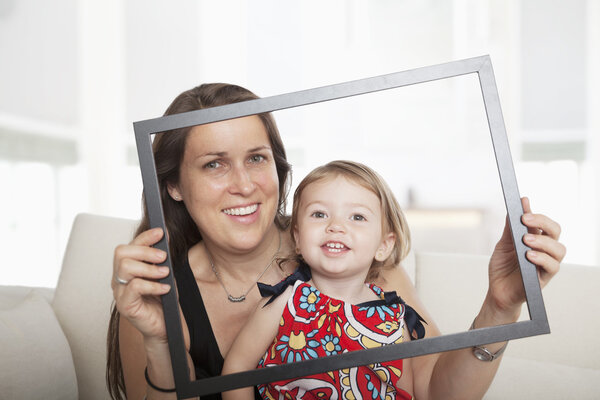 Mother and daughter holding up a picture frame