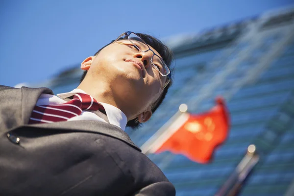 Empresário em frente a um prédio com bandeira chinesa — Fotografia de Stock