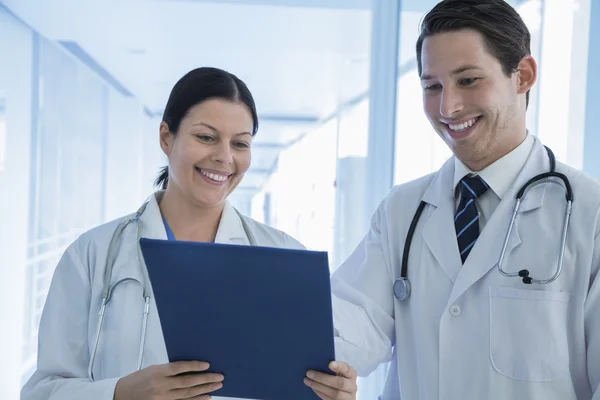 Médicos sonrientes mirando hacia abajo en un historial médico — Foto de Stock