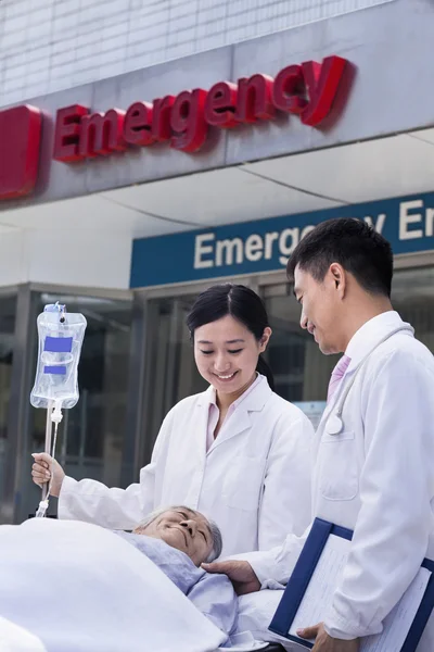 Ärzte tragen einen Patienten auf einer Trage ein — Stockfoto