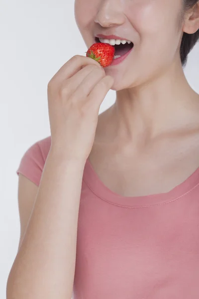 Mujer con camisa rosa comiendo una fresa — Foto de Stock