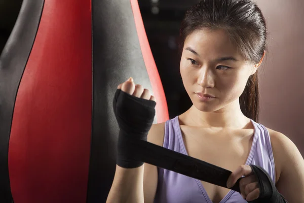 Mujer boxeadora envuelve sus muñecas en el gimnasio — Foto de Stock
