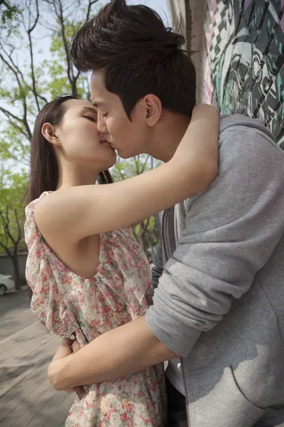 Couple kissing by a wall with graffiti — Stock Photo, Image