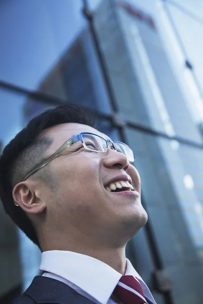 Affärsman som tittar upp med glas reflektion av skyskrapa — Stockfoto