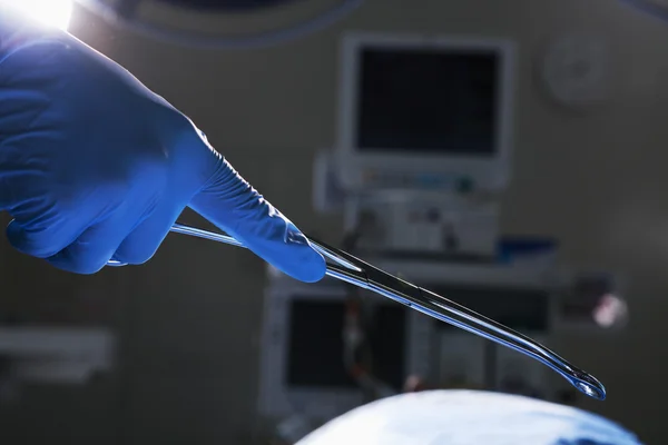 Mão de luva segurando tesoura cirúrgica — Fotografia de Stock