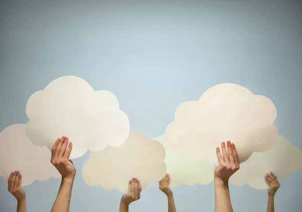 Multiple hands holding cut out paper clouds — Stock Photo, Image