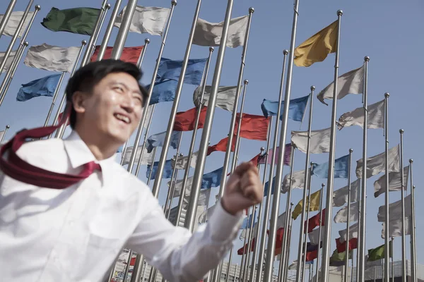 Businessman running with flagpoles in background — Stock Photo, Image