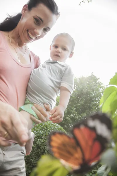 Mãe e filho apontando e olhando para uma borboleta — Fotografia de Stock
