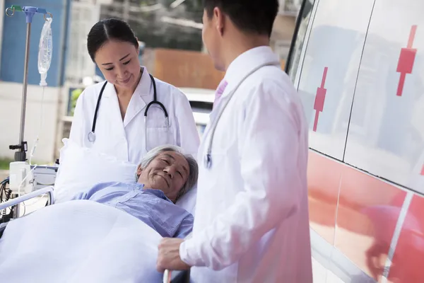 Doctors wheeling in a elderly patient on a stretcher — Stock Photo, Image