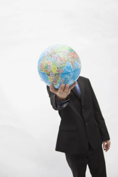 Businessman in a suit holding up a globe in front of his face — Stock Photo, Image