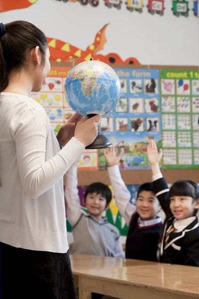 地理教学向学童使用地球仪的老师 — 图库照片