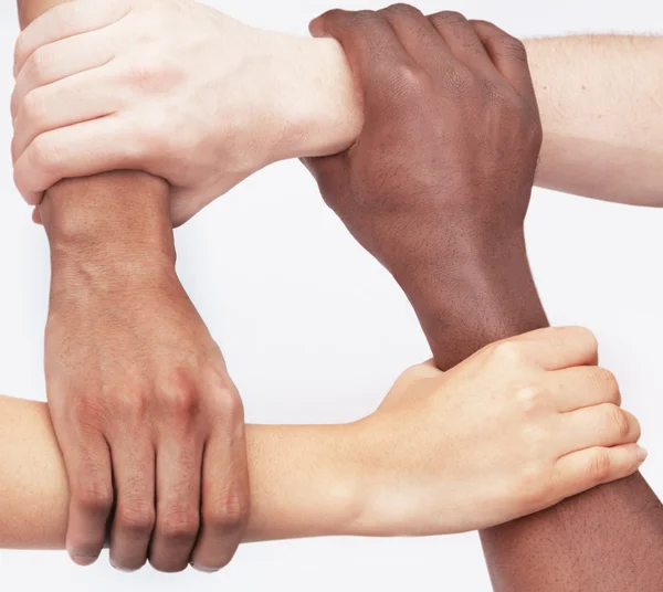 Four people holding each others wrists in a circle — Stock Photo, Image