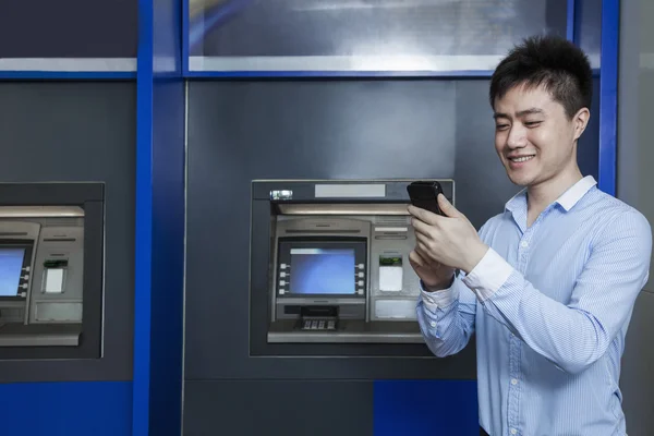 Businessman standing in front of an ATM — Stock Photo, Image