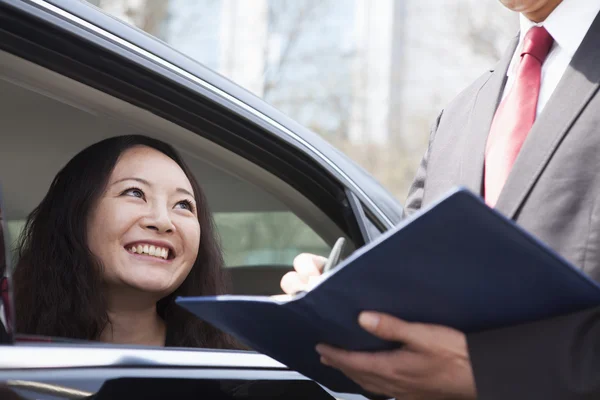 Donna seduta sul sedile posteriore dell'auto che parla con un collega di lavoro — Foto Stock