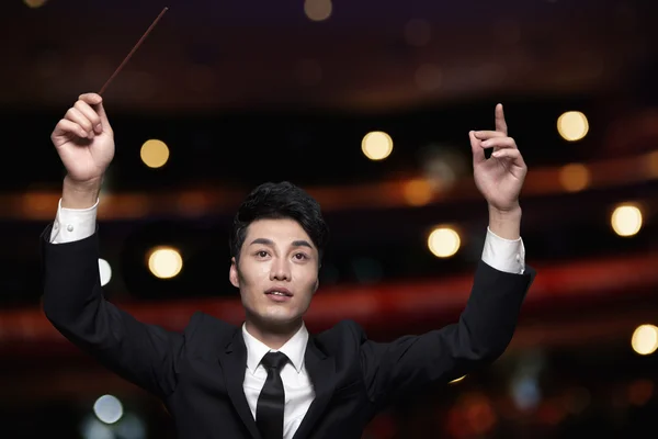 Conductor with baton raised at a performance — Stock Photo, Image