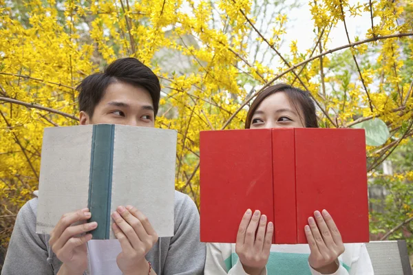 Casal olhando um para o outro sobre o topo de seus livros — Fotografia de Stock