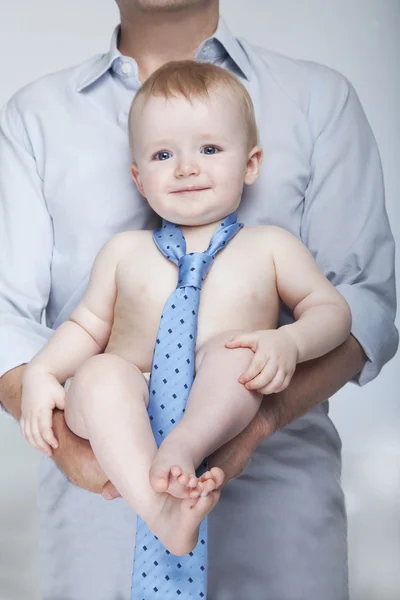 Bébé portant seulement une cravate et porté par son père — Photo