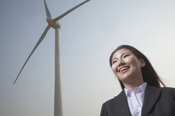 Businesswoman standing by a wind turbine — Stock Photo, Image