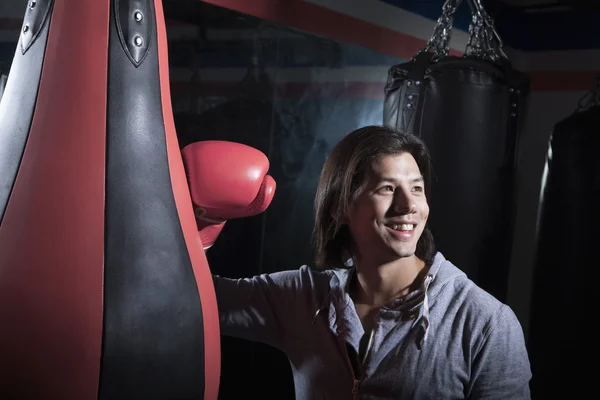 Мужчина в боксерском зале опирается на боксерскую грушу — стоковое фото
