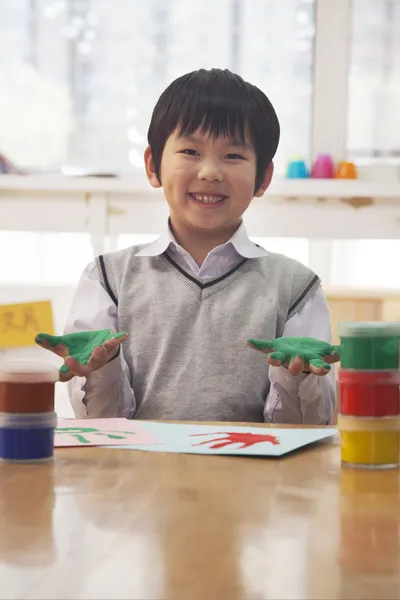 Smilende skolegutt fingermaleri i kunstklassen – stockfoto