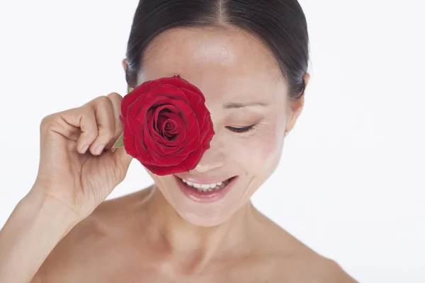 Vrouw met een rode roos voor haar oog — Stockfoto