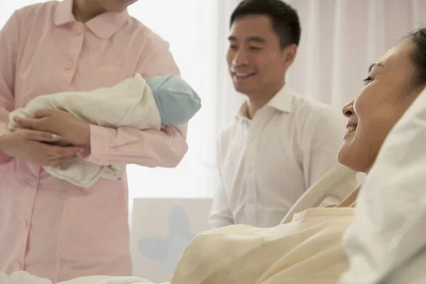 Медсестра держит новорожденного ребенка с матерью — стоковое фото