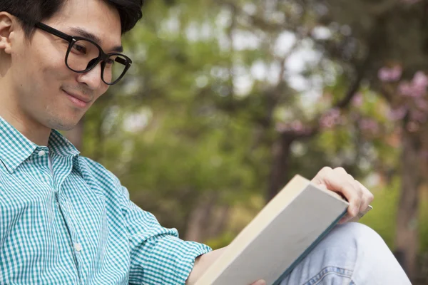 Homem desfrutando de seu livro em um parque — Fotografia de Stock