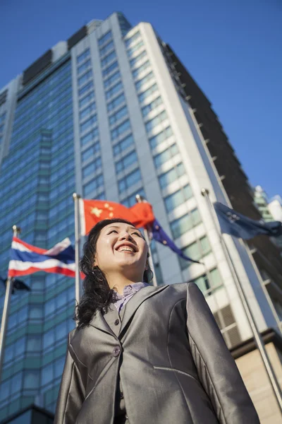 Businesswoman in front of a building with Chinese flag — Stock Photo, Image