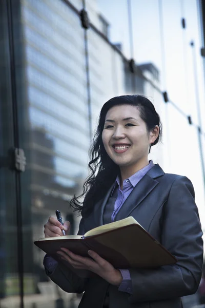 Businesswoman writing in her personal organizer — Stock Photo, Image