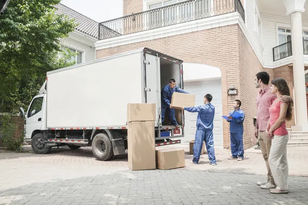 Coppia guardare i traslocatori spostare scatole dal furgone in movimento — Foto Stock