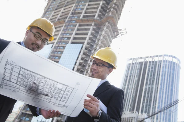 Architecten kijken naar blauwdruk op de bouwplaats — Stockfoto