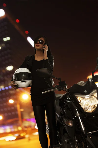 Kvinna prata i telefon bredvid hennes motorcykel — Stockfoto
