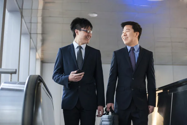 Businessmen coming up the escalator together — Stock Photo, Image
