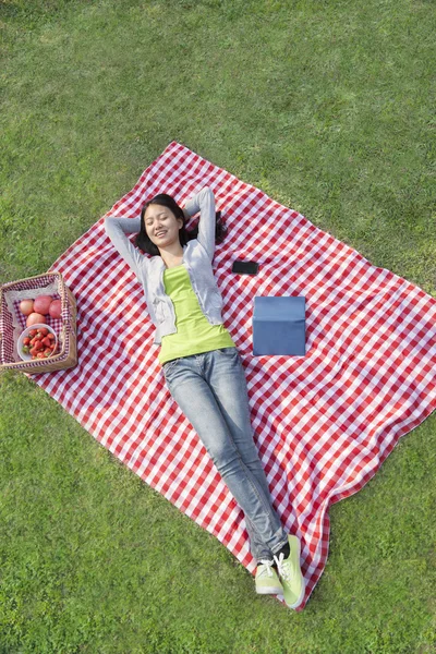 Женщина лежит на одеяле и отдыхает в парке — стоковое фото