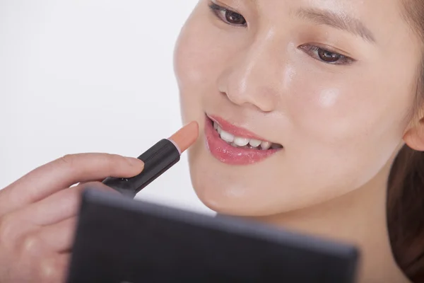 Woman applying lipstick in a mirror — Stock Photo, Image