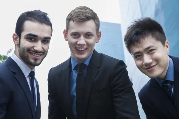 Три улыбающихся бизнесмена на улице — стоковое фото