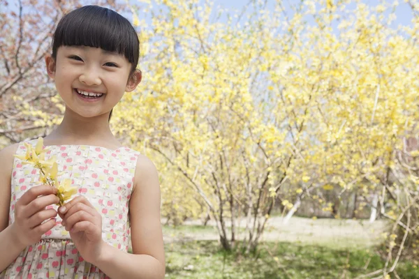 Girl holding a yellow flower in the park in springtime — Stock Photo, Image