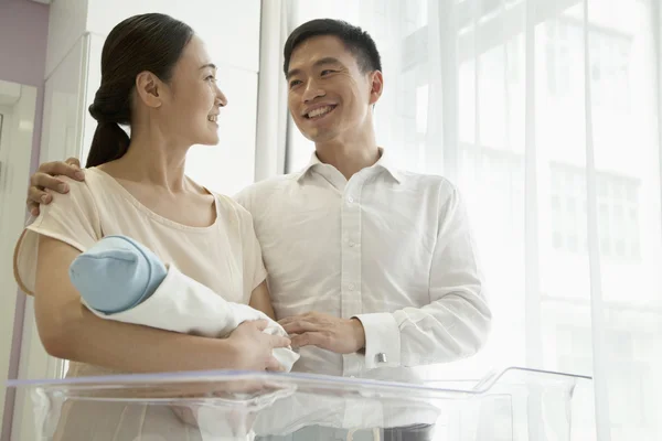 Young happy family holding their newborn — Stock Photo, Image