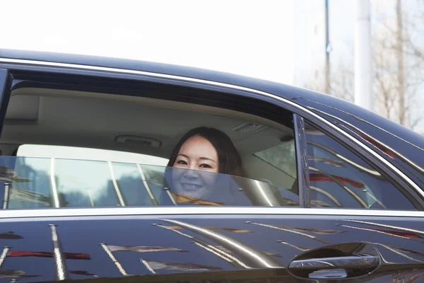 Mujer en el asiento trasero del coche mirando por la ventana — Foto de Stock