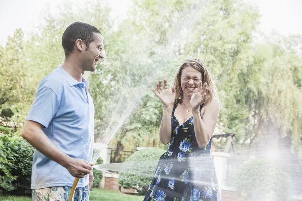 Couple spraying each other outside — Stock Photo, Image