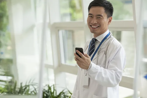 Doctor usando su teléfono en el vestíbulo del hospital — Foto de Stock